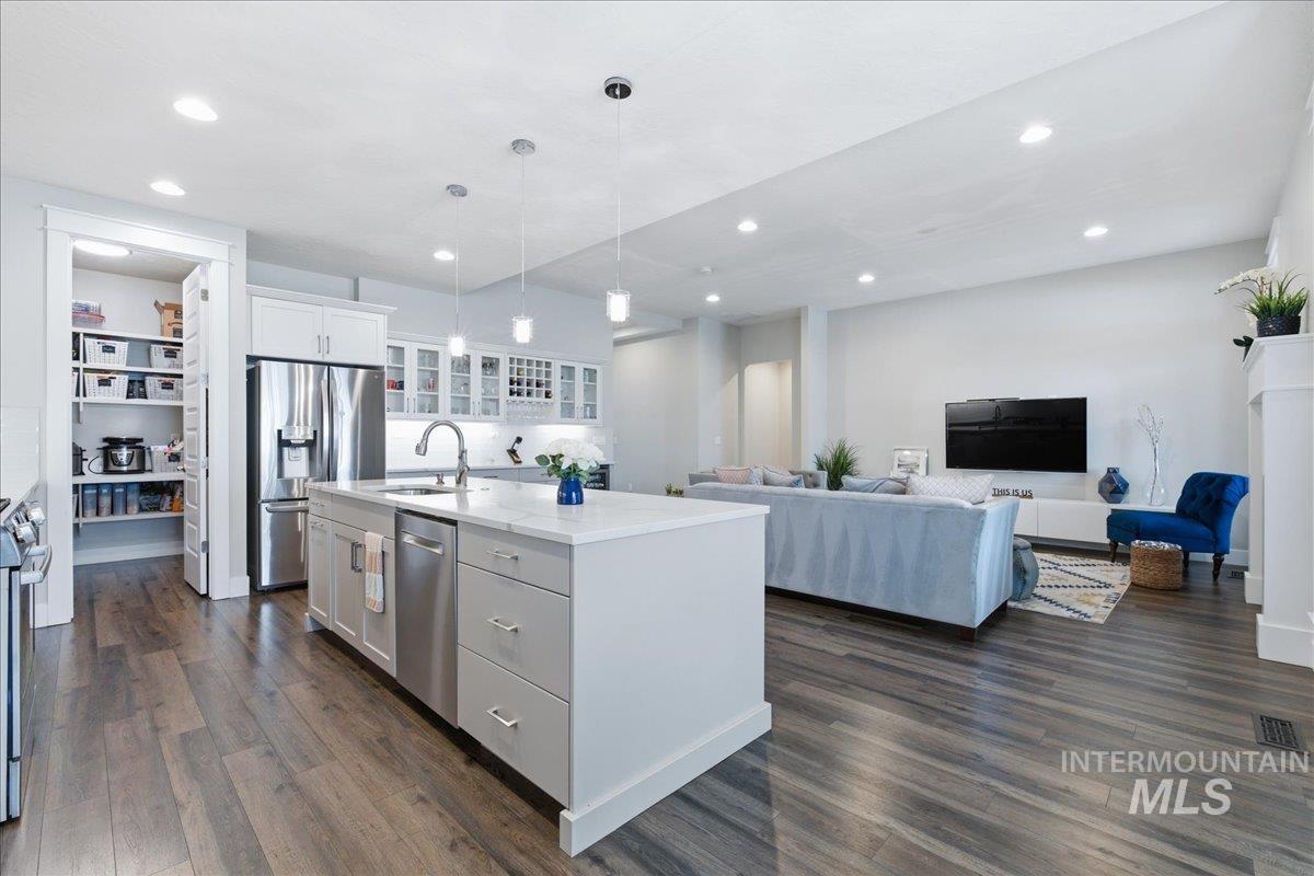 5154 South Twilight Mist Way Meridian, ID 83642 - Photo 47 of 47 Kitchen featuring a center island with sink, open floor plan, glass insert cabinets, dark wood-style floors, and decorative light fixtures