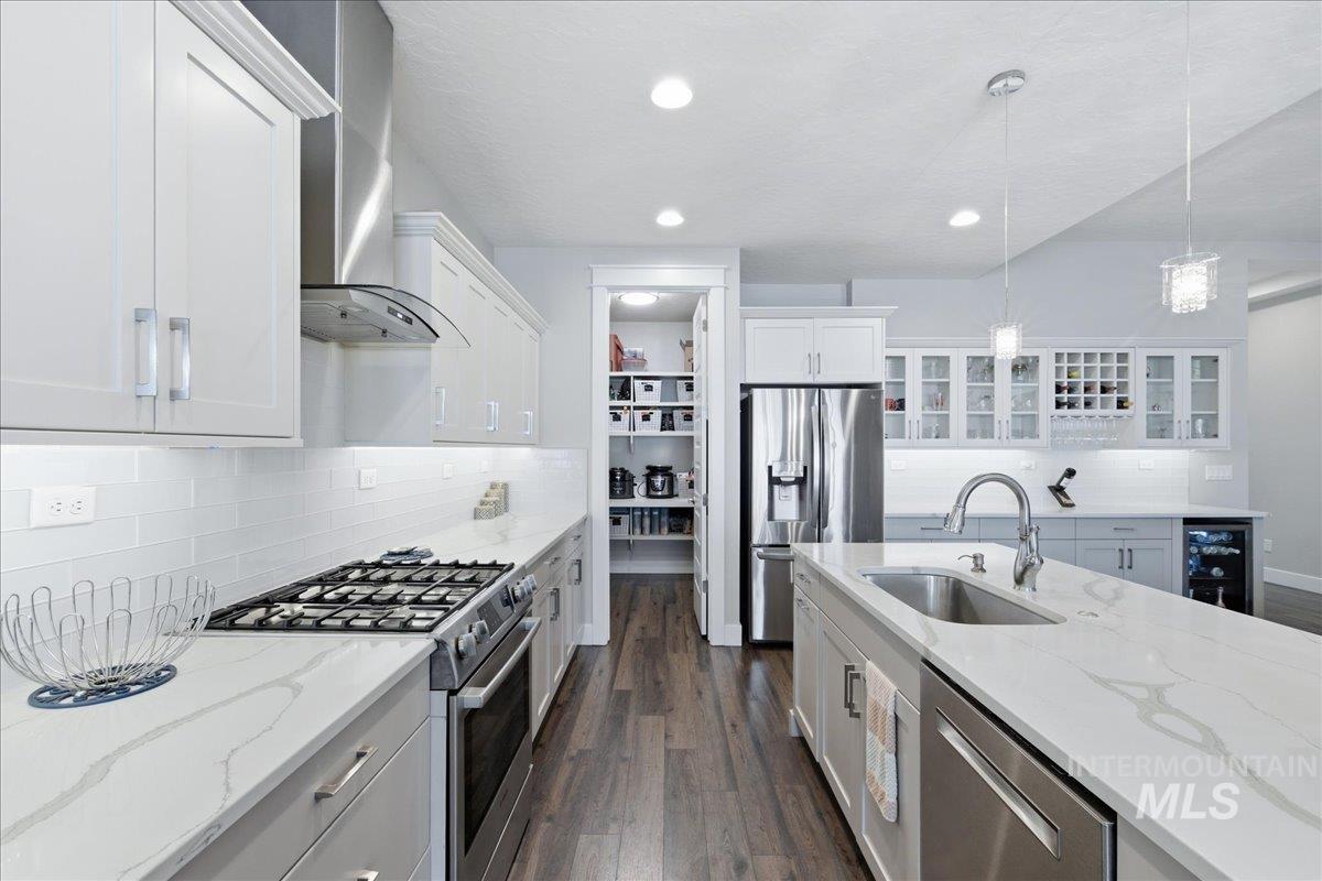 5154 South Twilight Mist Way Meridian, ID 83642 - Photo 15 of 47 Kitchen featuring stainless steel appliances, white cabinets, pendant lighting, dark wood finished floors, and beverage cooler