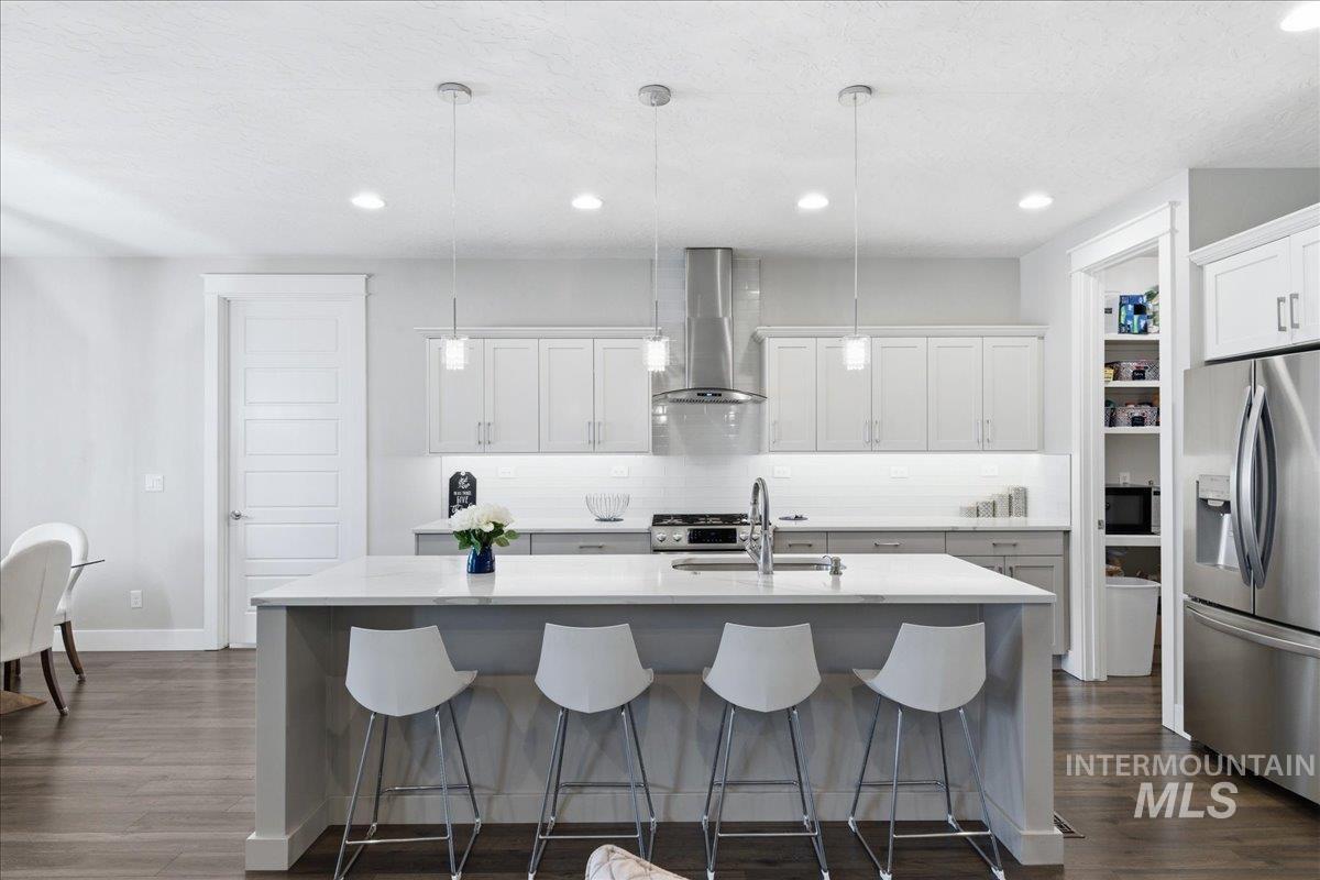 5154 South Twilight Mist Way Meridian, ID 83642 - Photo 17 of 47 Kitchen featuring stainless steel appliances, dark wood-style floors, an island with sink, and decorative light fixtures