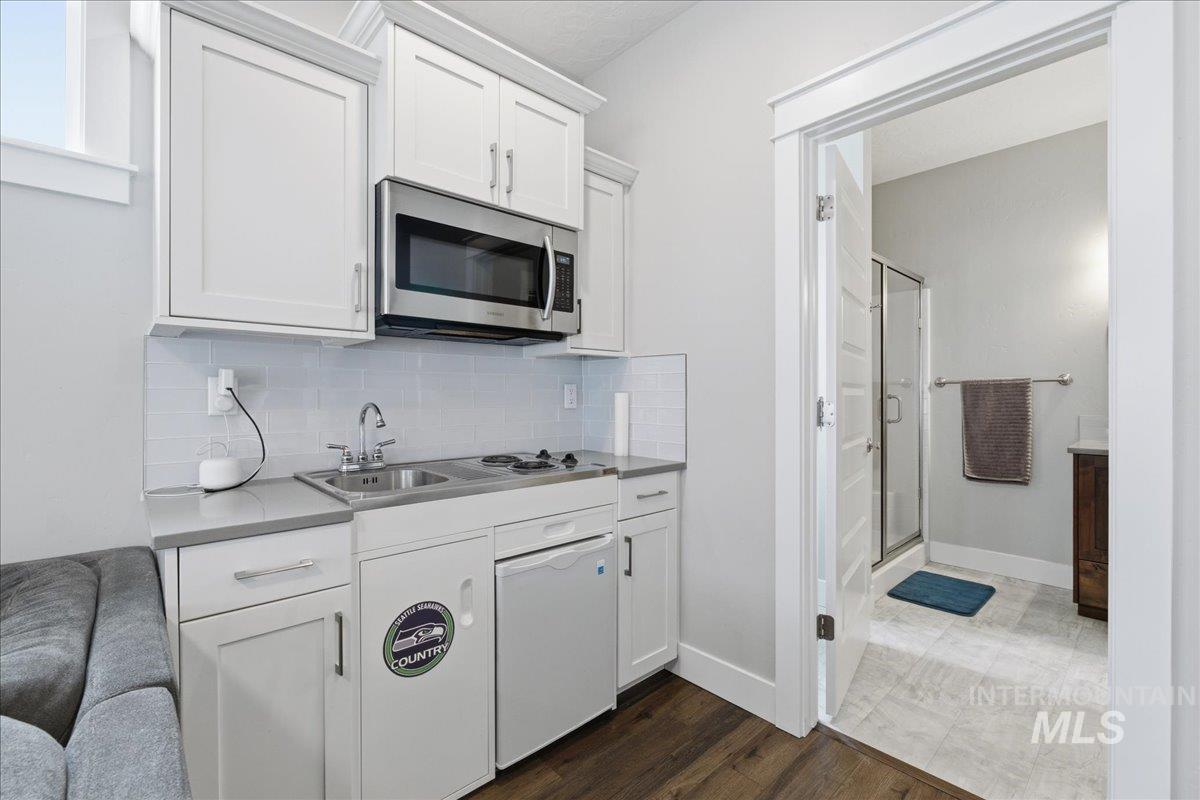 5154 South Twilight Mist Way Meridian, ID 83642 - Photo 32 of 47 Kitchen with stainless steel microwave, white cabinetry, dark wood finished floors, tasteful backsplash, and light countertops