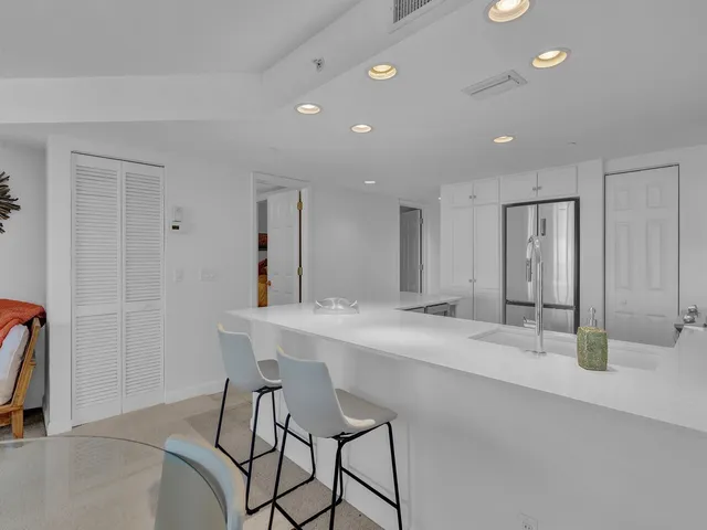 a large white kitchen with a sink and refrigerator
