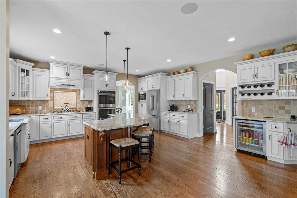 17 Applegate Road Medway, MA 02053 - Photo 13 of 42 a large open kitchen with a refrigerator a stove a sink a dining table and chairs with wooden floor