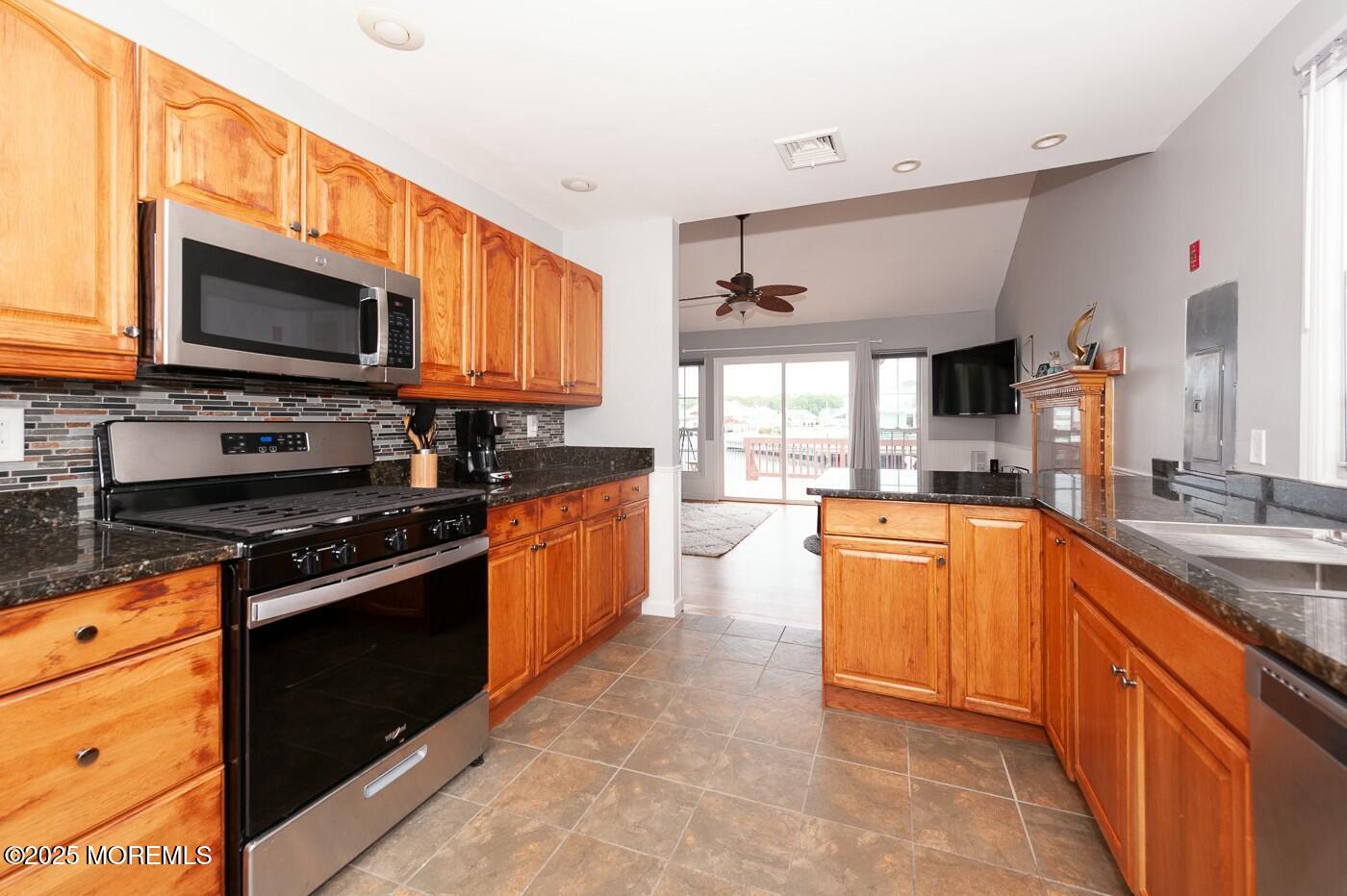 10 Commodore Drive Brick, NJ 08723 - Photo 6 of 27 a large kitchen with stainless steel appliances granite countertop a stove top oven a sink dishwasher a dining table and chairs with wooden floor
