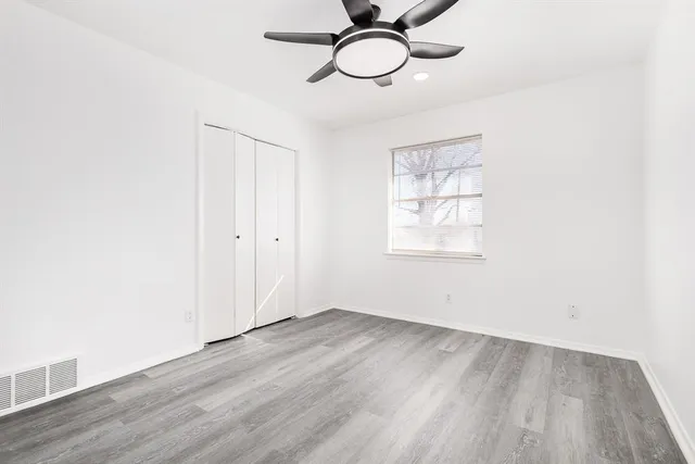 an empty room with wooden floor closet and windows