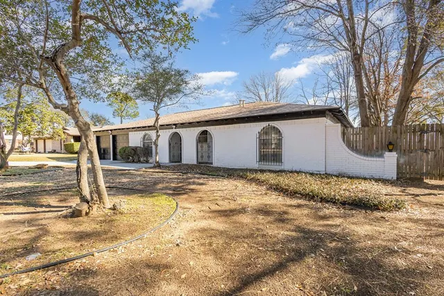 a backyard of a house with large trees and wooden fence