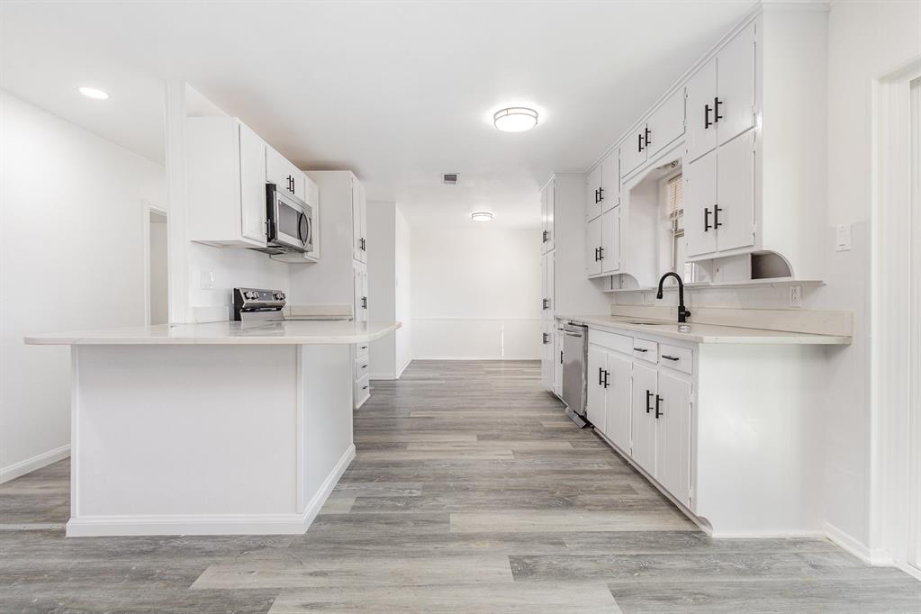 800 Overhill Court Hurst, TX 76053 - Photo 9 of 26 a large kitchen with stainless steel appliances kitchen island a sink dishwasher a stove and white cabinets with wooden floor