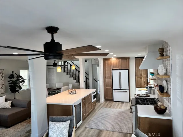 a living room with furniture kitchen view and a wooden floor