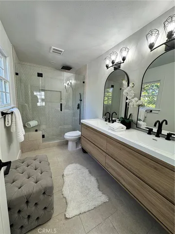 a bathroom with double vanity sinks a toilet a mirror and vanity