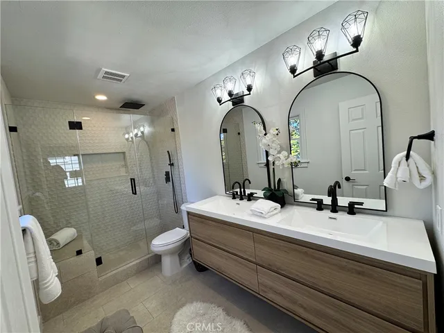 a bathroom with a double vanity sink toilet and shower