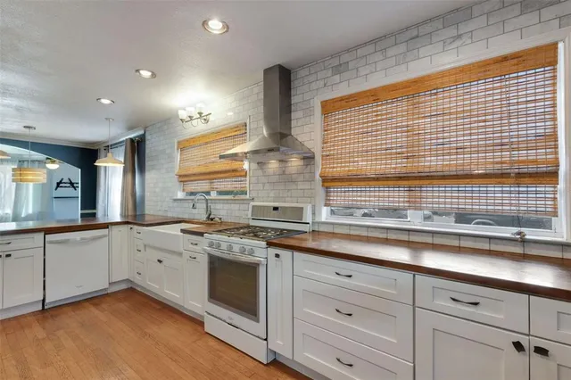 an empty room with wooden floor chandelier fan and windows