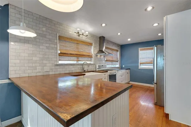 a kitchen with stainless steel appliances granite countertop a sink a stove and a wooden floors