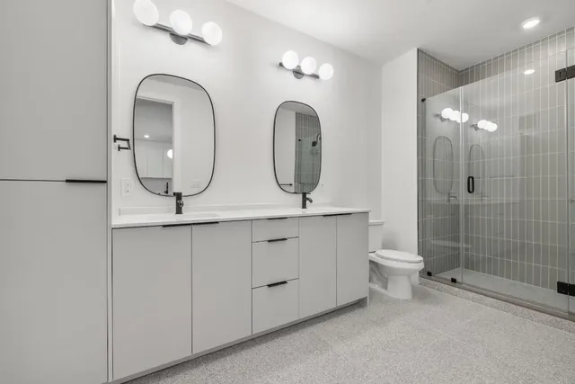 a bathroom with 2 sink a toilet and a mirror
