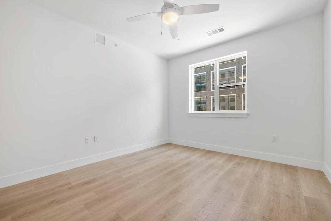1701 Simond Avenue, Unit 208 Austin, TX 78723 - Photo 16 of 30 an empty room with wooden floor and windows