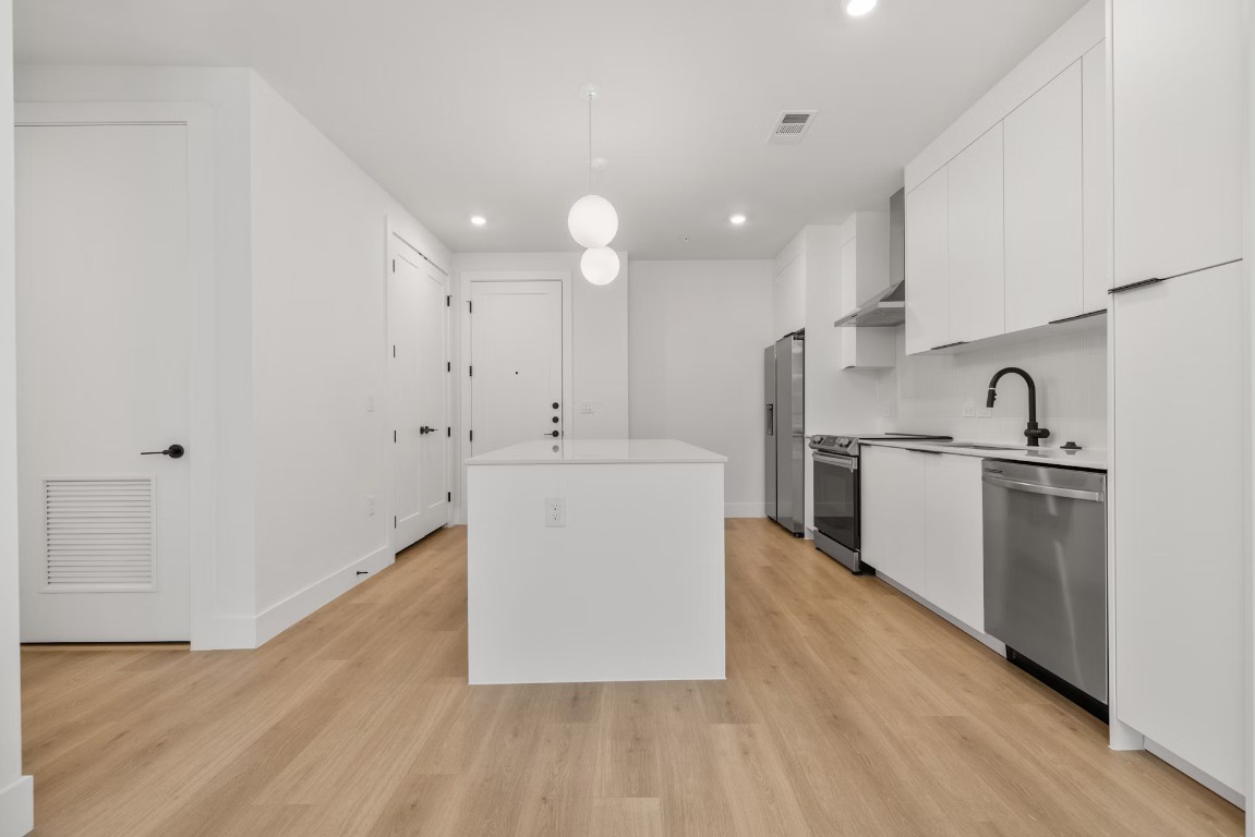 1701 Simond Avenue, Unit 208 Austin, TX 78723 - Photo 7 of 30 a large white kitchen with a sink a refrigerator and white cabinets