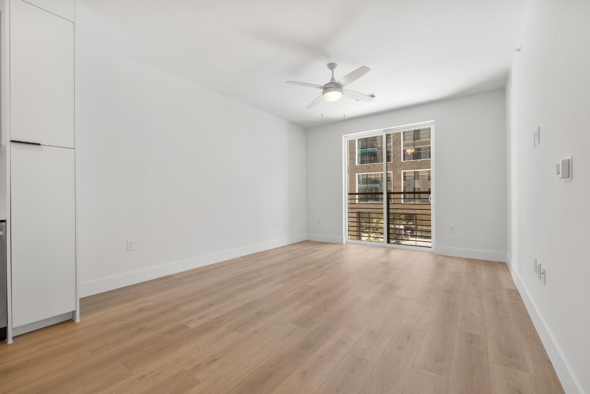 1701 Simond Avenue, Unit 208 Austin, TX 78723 - Photo 8 of 30 an empty room with wooden floor fan and windows