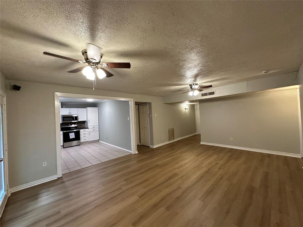 5908 Maple Lane Rowlett, TX 75089 - Photo 5 of 25 wooden floor in an empty room with a chandelier fan