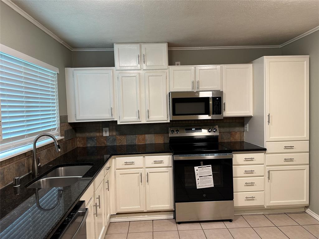 5908 Maple Lane Rowlett, TX 75089 - Photo 7 of 25 a kitchen with granite countertop a stove sink and microwave