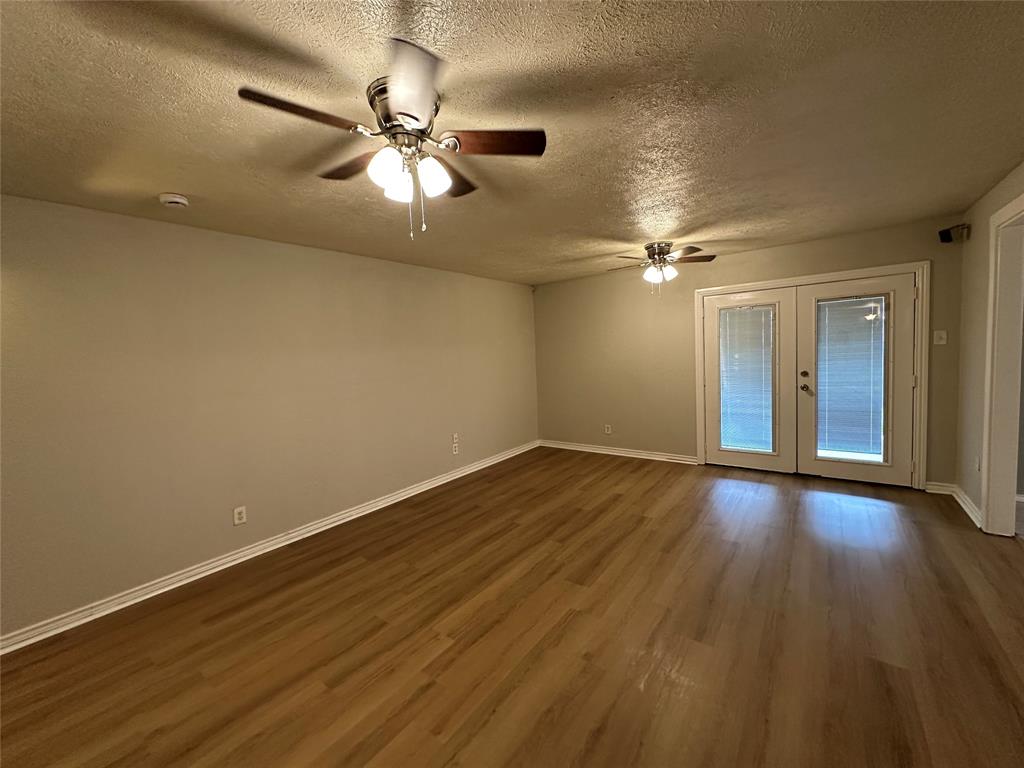 5908 Maple Lane Rowlett, TX 75089 - Photo 9 of 25 a view of an empty room with wooden floor and a ceiling fan
