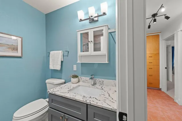 a bathroom with a granite countertop sink a toilet and shower
