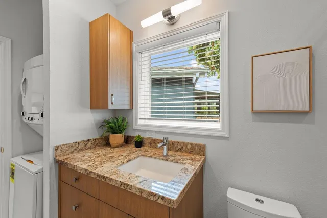 a bathroom with a granite countertop sink a toilet a mirror and shower