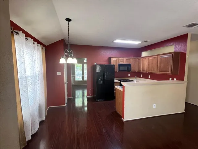 a kitchen with stainless steel appliances granite countertop a refrigerator a sink dishwasher a stove and a refrigerator with wooden floor