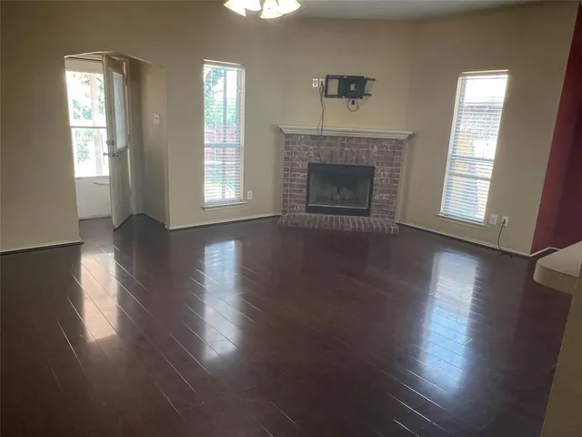 an empty room with wooden floor fireplace and windows