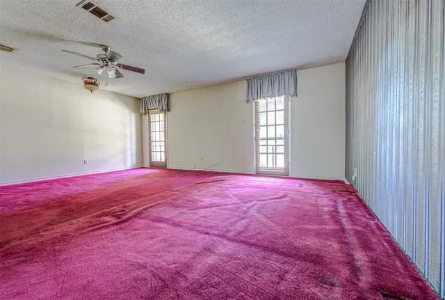a view of a big room with windows and chandelier fan