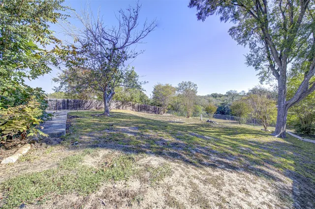 a view of dirt field with trees around
