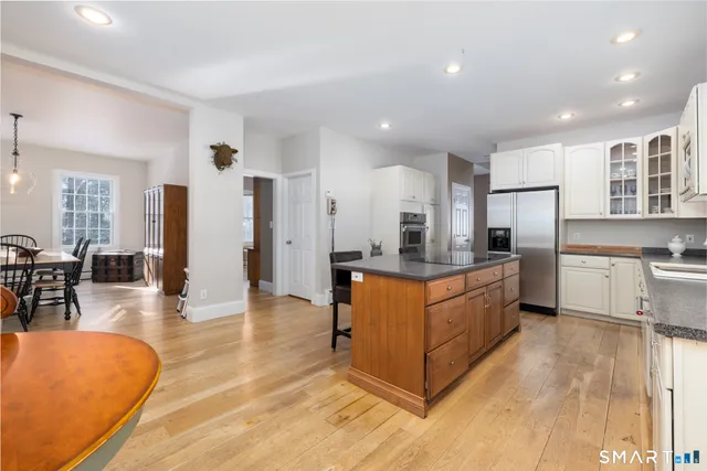 a large kitchen with stainless steel appliances granite countertop a refrigerator a stove a sink a dining table and chairs with wooden floor