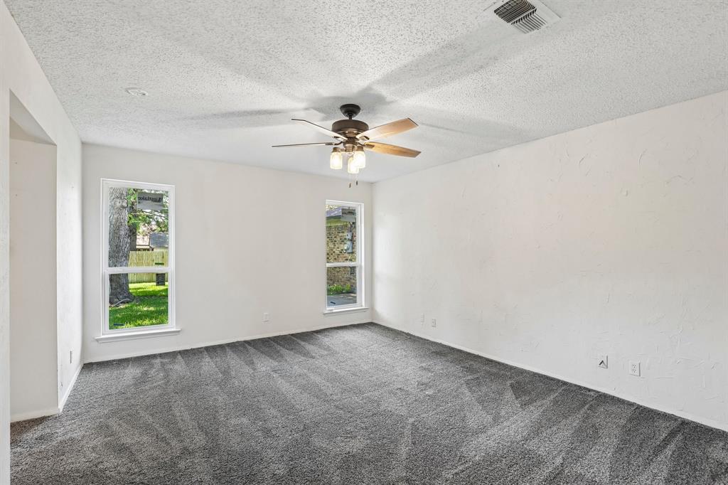 1600 South Timber Court Benbrook, TX 76126 - Photo 19 of 30 Spacious room featuring gray textured carpeting, white painted walls, and a ceiling fan with light fixture