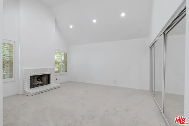 an empty room with a fireplace and windows