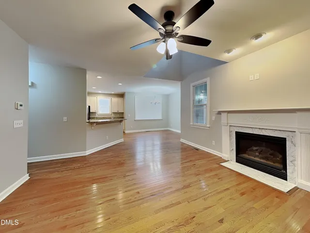 an empty room with wooden floor fireplace and windows