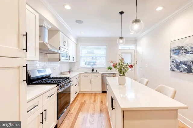 a kitchen with stainless steel appliances kitchen island granite countertop a sink a stove and a wooden floors