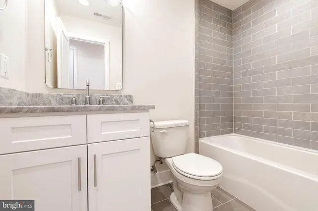 a bathroom with a granite countertop toilet sink and mirror