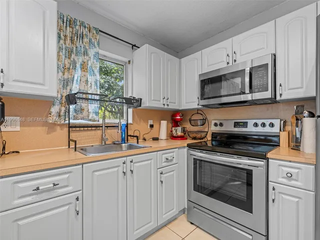 a kitchen with cabinets stainless steel appliances a sink and a window