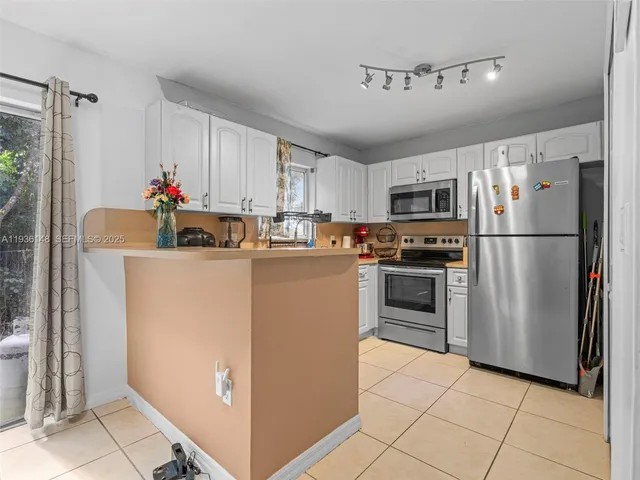 a kitchen with kitchen island white cabinets and refrigerator