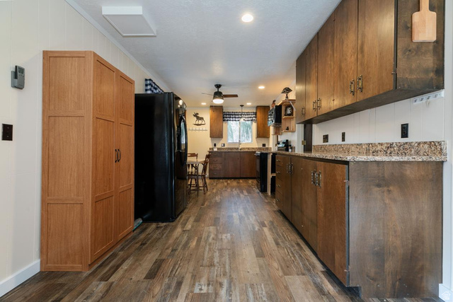 1105 Litz Road Preston, ID 83263 - Photo 7 of 24 Kitchen with black appliances, dark wood-style floors, hanging light fixtures, ceiling fan, and granite countertops