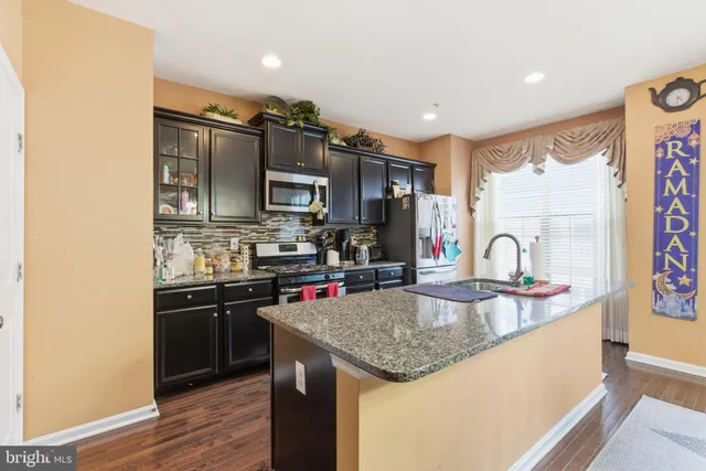 a kitchen with stainless steel appliances granite countertop a sink refrigerator and microwave