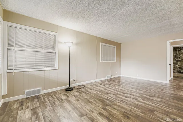 a view of an empty room with window and wooden floor