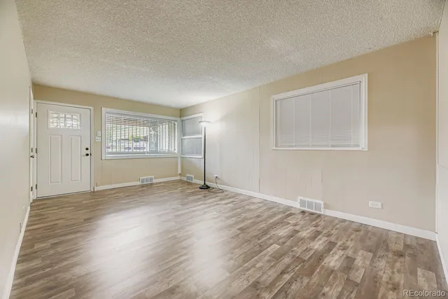an empty room with wooden floor and windows