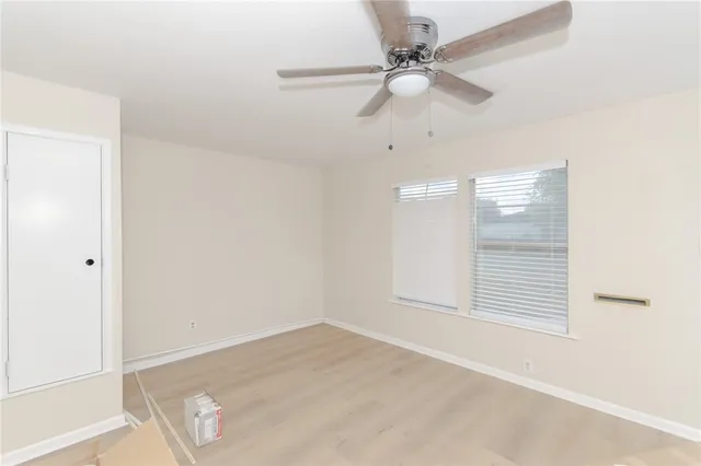 an empty room with a ceiling fan and wooden floor