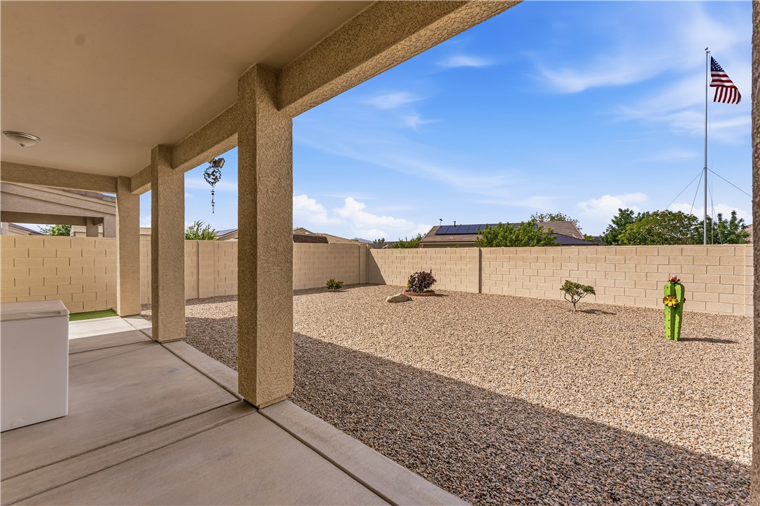 4143 North Stampede Road Kingman, AZ 86401 - Photo 39 of 42 Covered patio with textured stucco pillars, concrete flooring, and an expansive gravel yard enclosed by a block wall