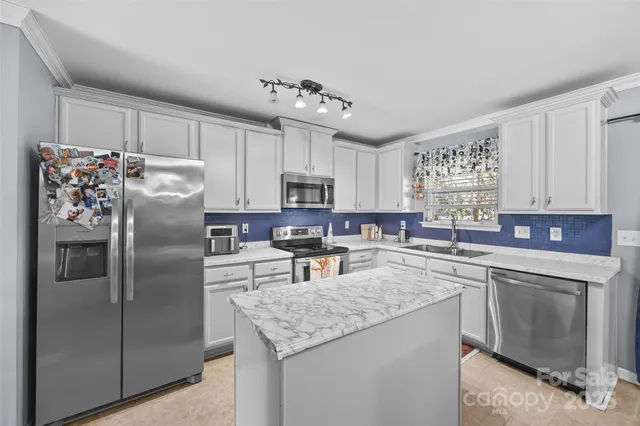 a kitchen with a stove a sink dishwasher a dining table and chairs with wooden floor