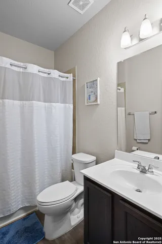 a bathroom with a sink a toilet and shower curtain