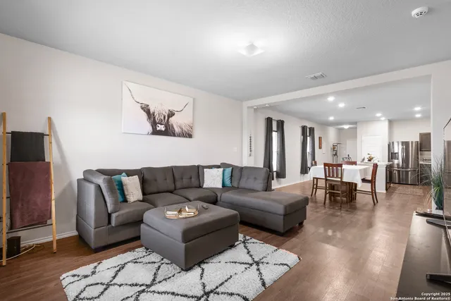 a living room with furniture and a dining table with wooden floor