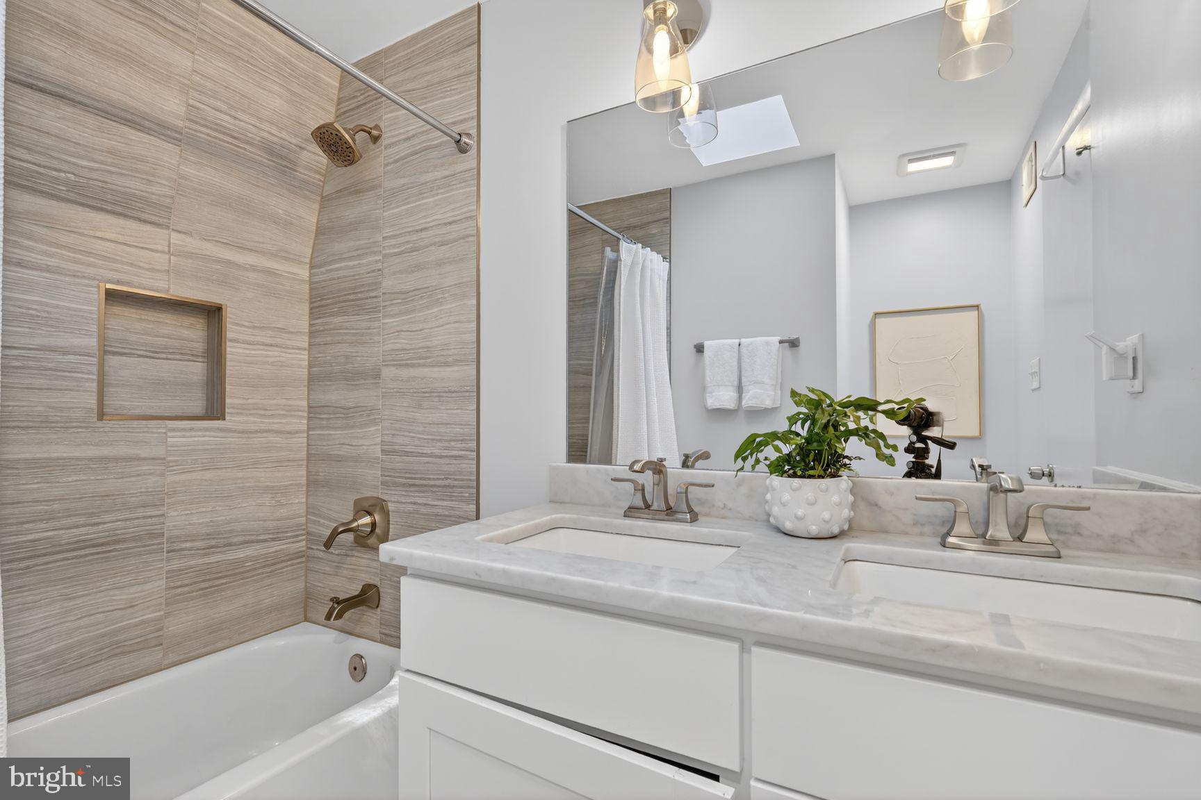 11201 Wedge Drive Reston, VA 20190 - Photo 25 of 31 a bathroom with a granite countertop sink a mirror a bathtub and shower