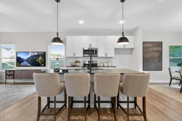 a kitchen with stainless steel appliances granite countertop a dining table chairs stove a refrigerator and cabinets