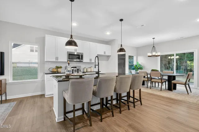 a kitchen with stainless steel appliances kitchen island granite countertop a dining table chairs stove a sink and a window