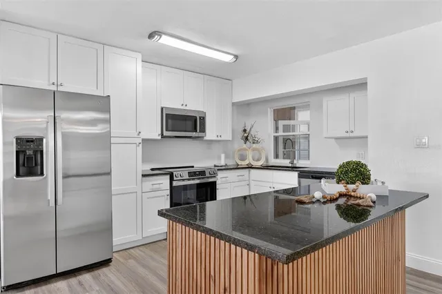 a kitchen with stainless steel appliances granite countertop a sink a refrigerator and a stove top oven