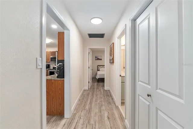a view of a hallway with wooden floor and a bathroom